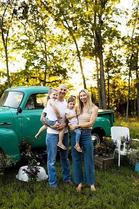 Family posing near teal vintage truck with wildflowers in Warrenton Missouri