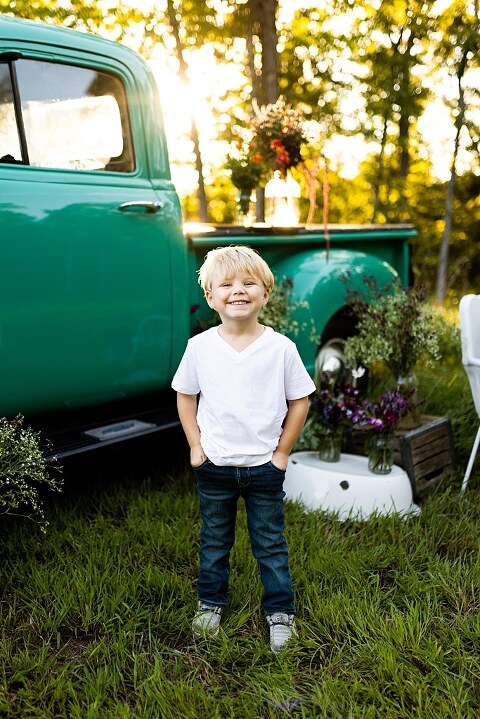 Blended family near teal vintage truck and fresh wildflowers in High Hill Missouri at golden hour
