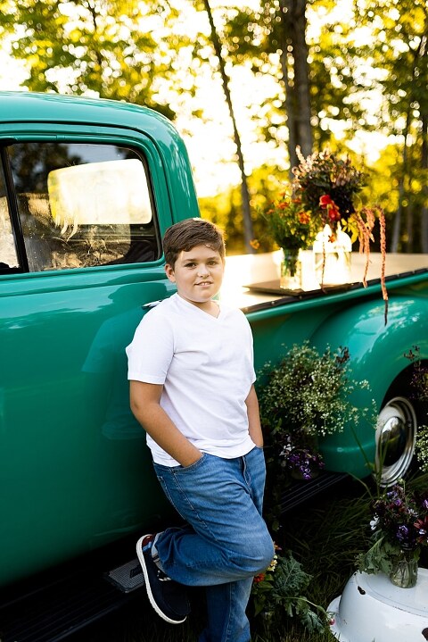 Blended family near teal vintage truck and fresh wildflowers in High Hill Missouri at golden hour