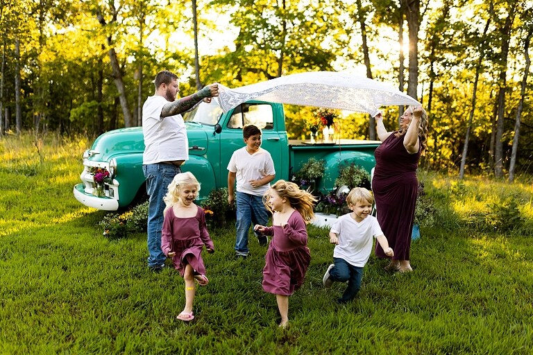 Blended family near teal vintage truck and fresh wildflowers in High Hill Missouri at golden hour