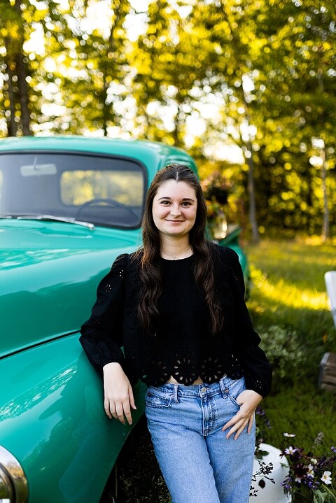 High school senior with teal truck and wildflowers during golden hour in High Hill Missouri
