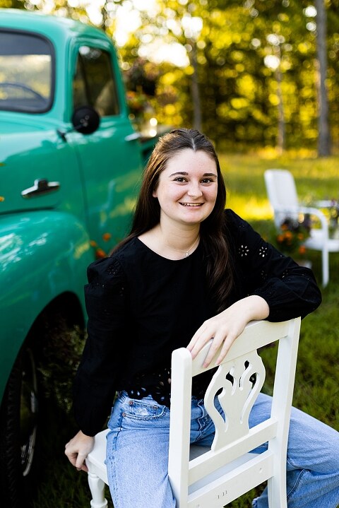 High school senior with teal truck and wildflowers during golden hour in High Hill Missouri