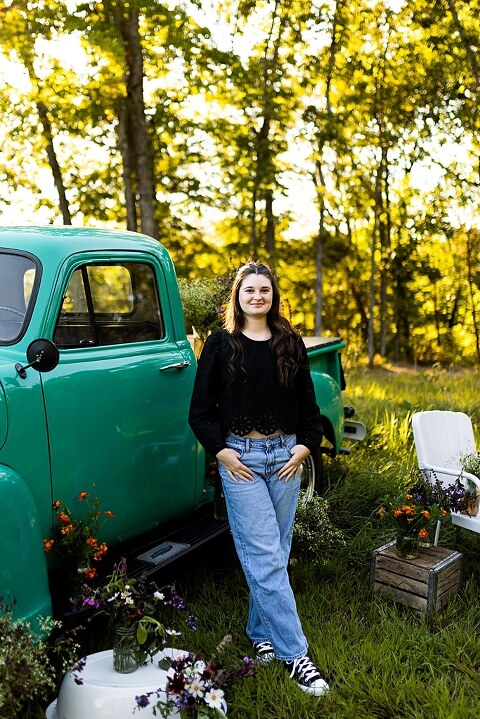 High school senior with teal truck and wildflowers during golden hour in High Hill Missouri