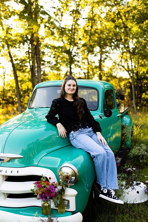 High school senior with teal truck and wildflowers during golden hour in High Hill Missouri