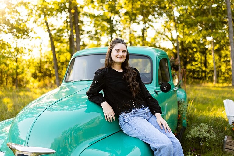 High school senior with teal truck and wildflowers during golden hour in High Hill Missouri