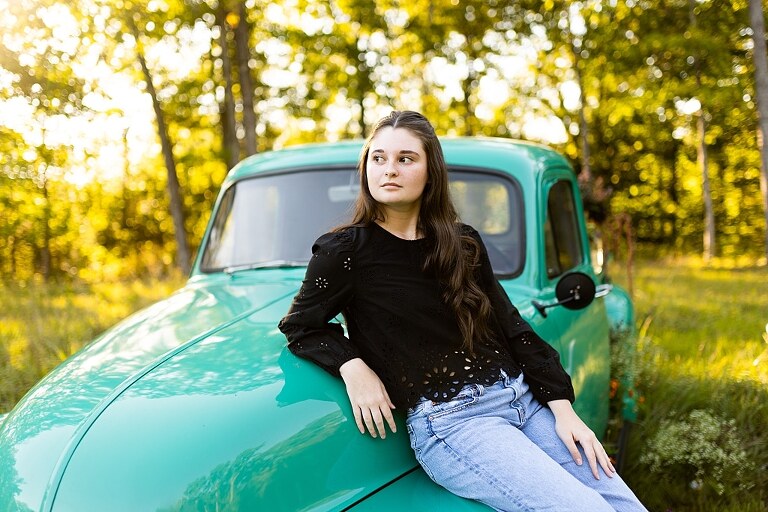 High school senior with teal truck and wildflowers during golden hour in High Hill Missouri