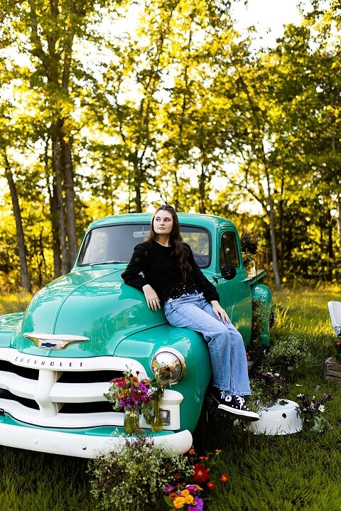 High school senior with teal truck and wildflowers during golden hour in High Hill Missouri