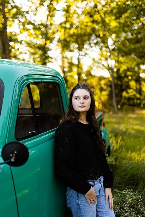 High school senior with teal truck and wildflowers during golden hour in High Hill Missouri