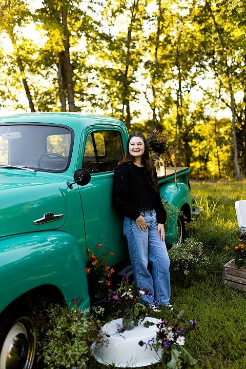 High school senior with teal truck and wildflowers during golden hour in High Hill Missouri