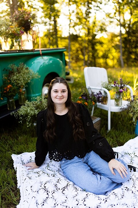 High school senior with teal truck and wildflowers during golden hour in High Hill Missouri