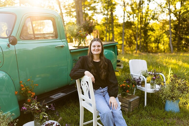 High school senior with teal truck and wildflowers during golden hour in High Hill Missouri