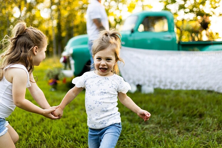 Family posing near teal vintage truck with wildflowers in Warrenton Missouri