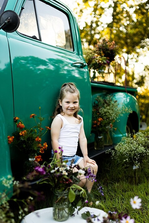 Family posing near teal vintage truck with wildflowers in Warrenton Missouri