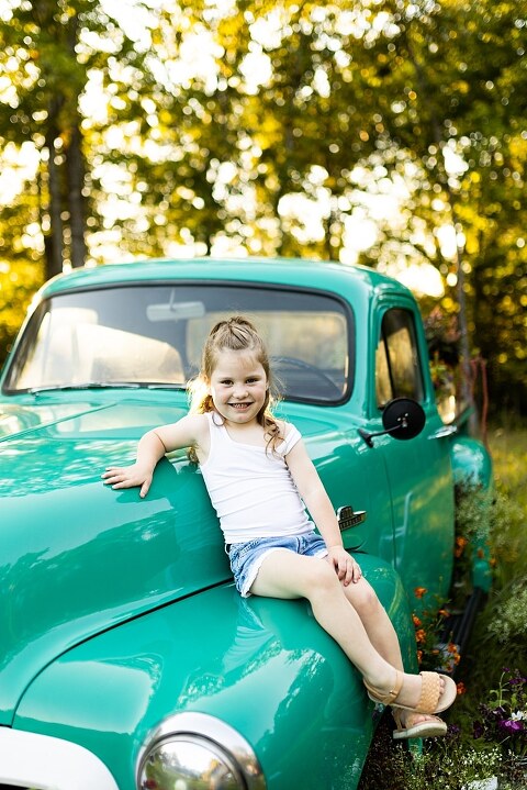 Family posing near teal vintage truck with wildflowers in Warrenton Missouri