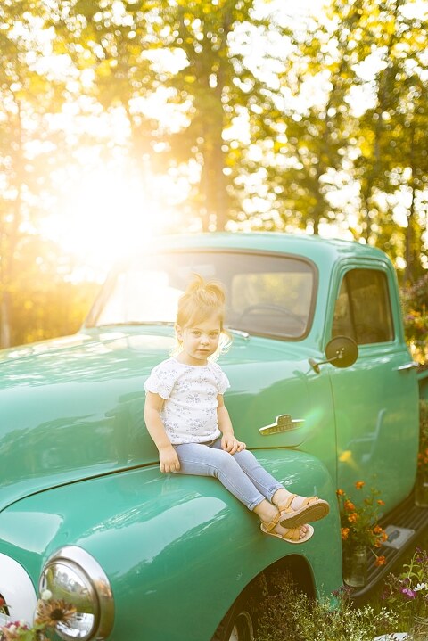 Family posing near teal vintage truck with wildflowers in Warrenton Missouri