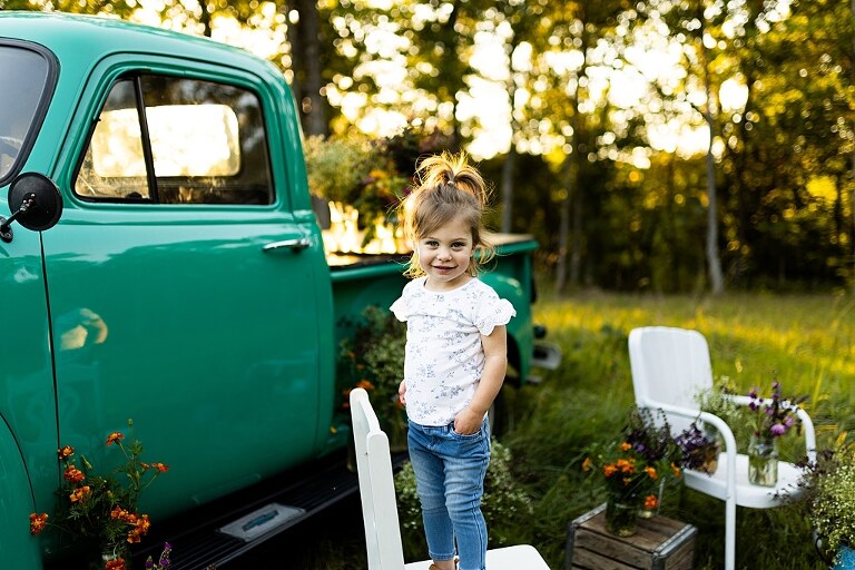 Family posing near teal vintage truck with wildflowers in Warrenton Missouri