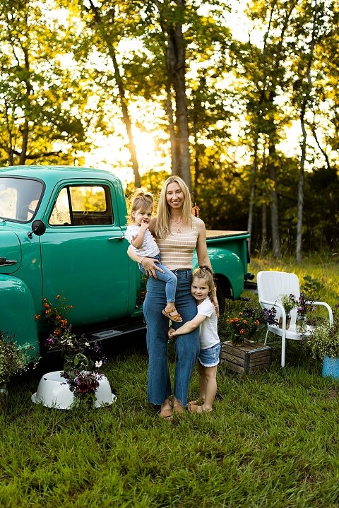 Family posing near teal vintage truck with wildflowers in Warrenton Missouri