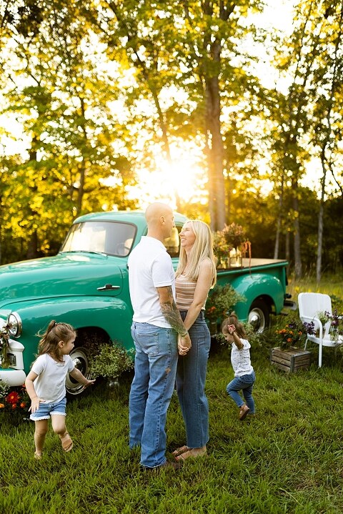 Family posing near teal vintage truck with wildflowers in Warrenton Missouri