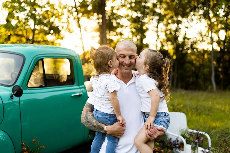 Family posing near teal vintage truck with wildflowers in Warrenton Missouri
