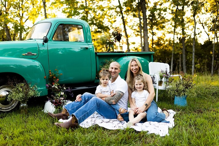 Family posing near teal vintage truck with wildflowers in Warrenton Missouri Family Flower Truck Mini Session