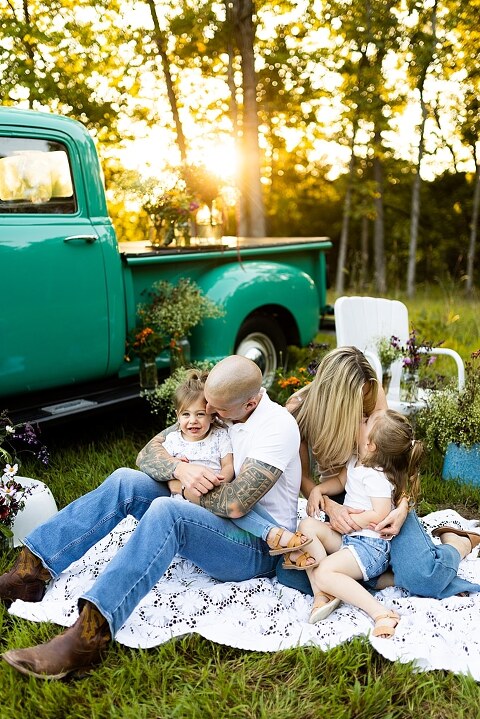 Family posing near teal vintage truck with wildflowers in Warrenton Missouri Family Flower Truck Mini Session