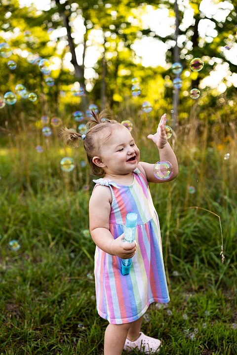 Playful family photo session in High Hill Missouri with mom and four kids enjoying bubbles, sprinkler fun, mud, and sunshine during summertime minis.
