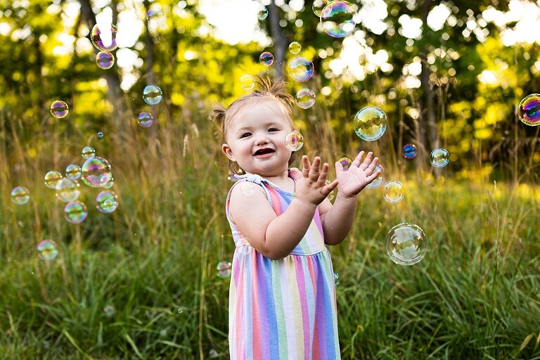 Playful family photo session in High Hill Missouri with mom and four kids enjoying bubbles, sprinkler fun, mud, and sunshine during summertime minis.