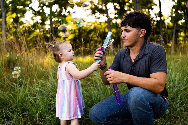 Playful family photo session in High Hill Missouri with mom and four kids enjoying bubbles, sprinkler fun, mud, and sunshine during summertime minis.