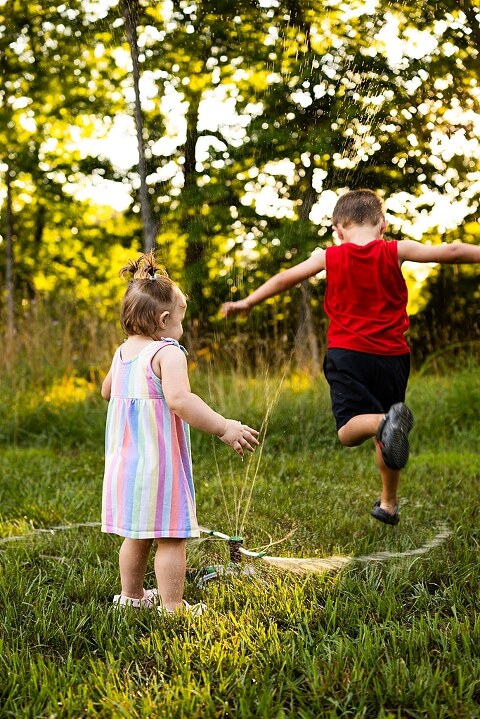 Playful family photo session in High Hill Missouri with mom and four kids enjoying bubbles, sprinkler fun, mud, and sunshine during summertime minis.