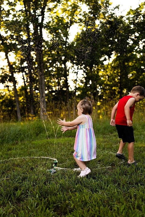 Playful family photo session in High Hill Missouri with mom and four kids enjoying bubbles, sprinkler fun, mud, and sunshine during summertime minis.