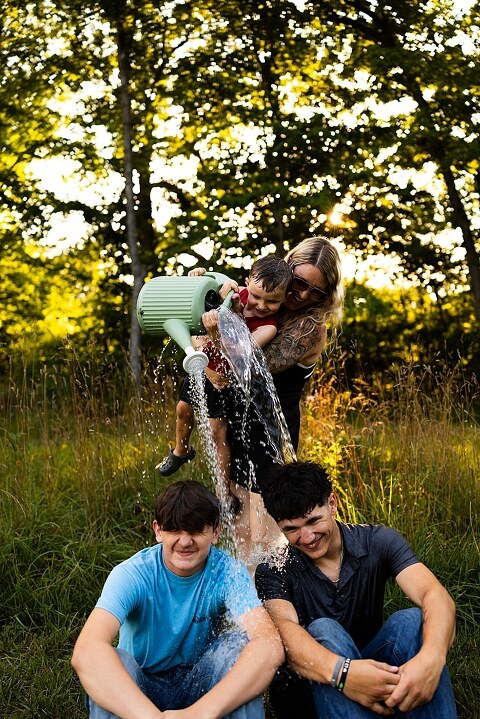 Playful family photo session in High Hill Missouri with mom and four kids enjoying bubbles, sprinkler fun, mud, and sunshine during summertime minis.