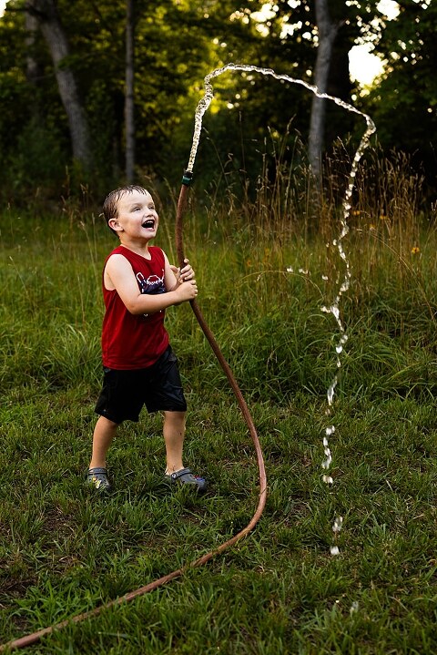 Playful family photo session in High Hill Missouri with mom and four kids enjoying bubbles, sprinkler fun, mud, and sunshine during summertime minis.