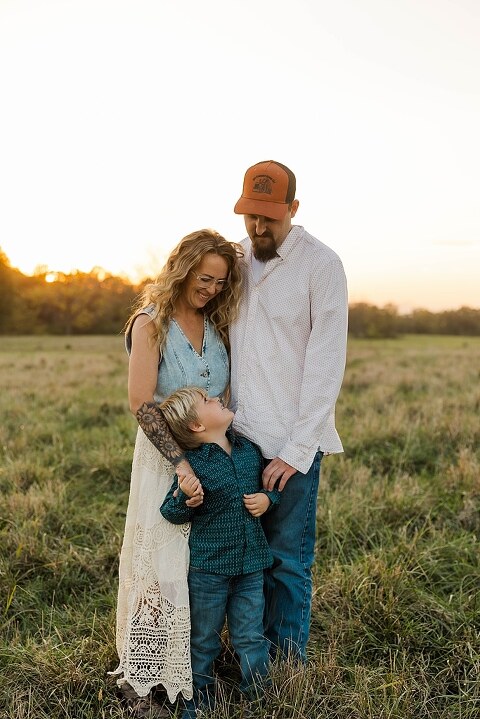 Family standing together in a warm country field during their 90’s style session.
Parents holding their kids with soft golden light behind them.
Family walking through a field during a country-inspired photo shoot.
Close-up of parents smiling during their session with Taylor Ligon Photography.
Kids laughing while standing between their parents in a sunny field.