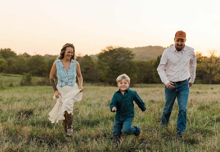 Family standing together in a warm country field during their 90’s style session.
Parents holding their kids with soft golden light behind them.
Family walking through a field during a country-inspired photo shoot.
Close-up of parents smiling during their session with Taylor Ligon Photography.
Kids laughing while standing between their parents in a sunny field.