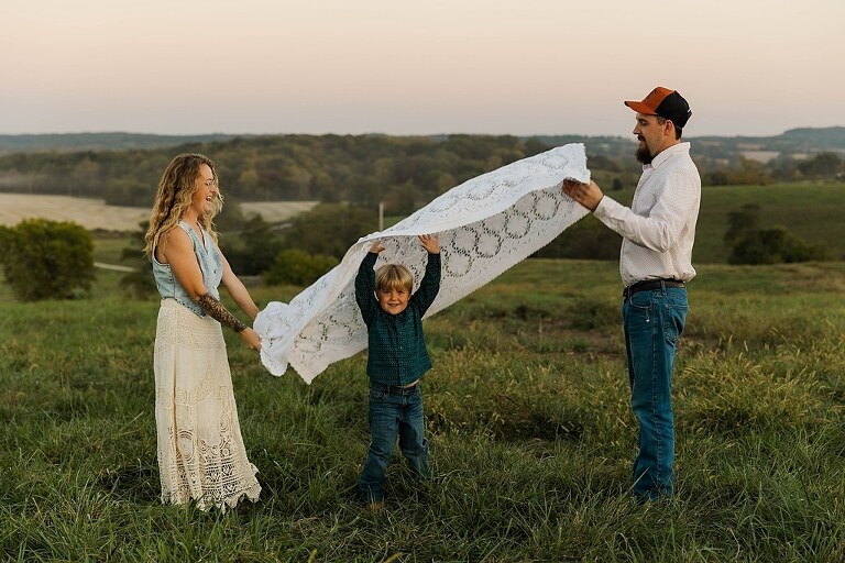 Family standing together in a warm country field during their 90’s style session.
Parents holding their kids with soft golden light behind them.
Family walking through a field during a country-inspired photo shoot.
Close-up of parents smiling during their session with Taylor Ligon Photography.
Kids laughing while standing between their parents in a sunny field.