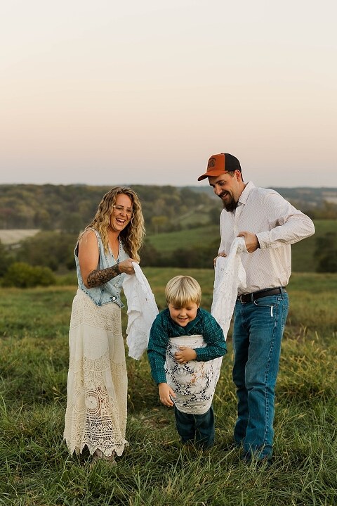Family standing together in a warm country field during their 90’s style session.
Parents holding their kids with soft golden light behind them.
Family walking through a field during a country-inspired photo shoot.
Close-up of parents smiling during their session with Taylor Ligon Photography.
Kids laughing while standing between their parents in a sunny field.