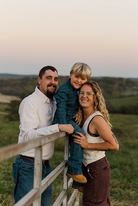 Family standing together in a warm country field during their 90’s style session.
Parents holding their kids with soft golden light behind them.
Family walking through a field during a country-inspired photo shoot.
Close-up of parents smiling during their session with Taylor Ligon Photography.
Kids laughing while standing between their parents in a sunny field.
