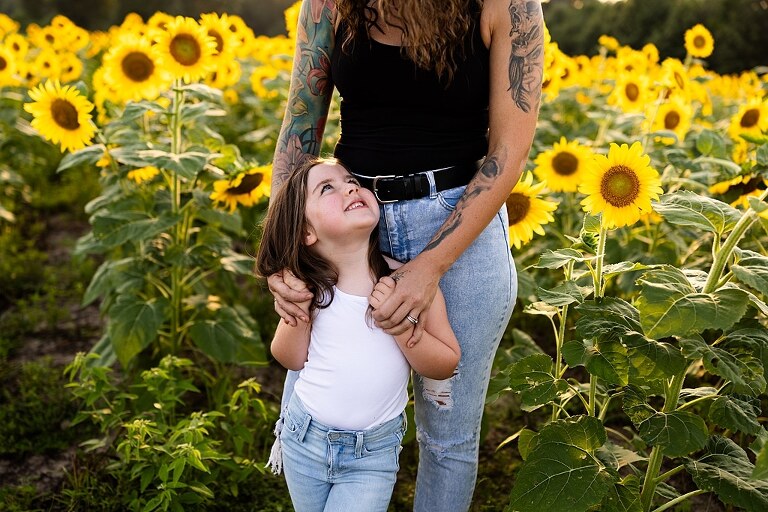 Kids laughing together in a sunflower field during summer family photos | Children exploring sunflowers during family session in Missouri | Missouri photographer Missouri outdoor photographer warrenton MO Jonesburg Montgomery 