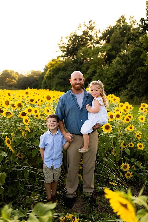 Family of four during sunflower mini photo session in Jonesburg Missouri | Kids smiling in sunflower field during family tradition photo shoot | Family cuddles in sunflower field during summer photos | Missouri Photographer | Outdoor photographer 