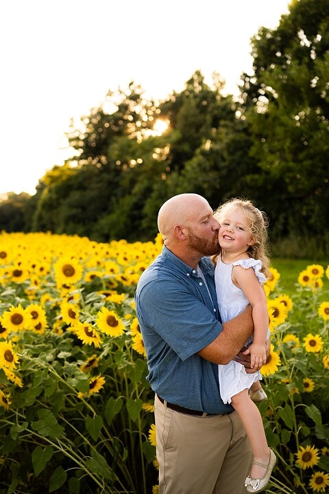 Family of four during sunflower mini photo session in Jonesburg Missouri | Kids smiling in sunflower field during family tradition photo shoot | Family cuddles in sunflower field during summer photos | Missouri Photographer | Outdoor photographer 
