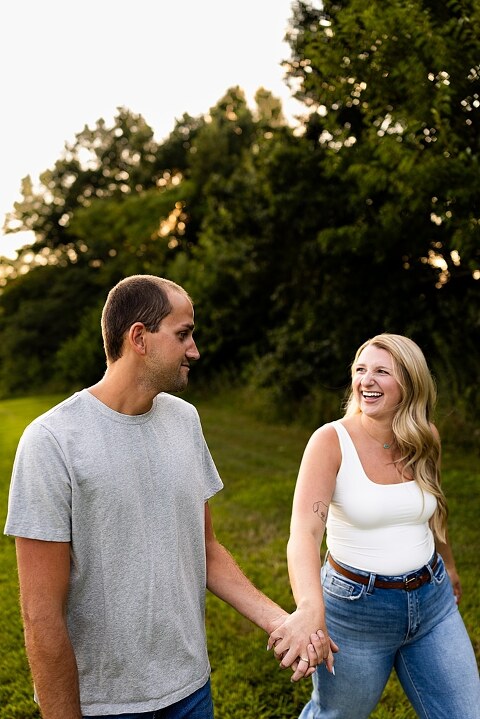 Extended family standing together in a sunflower field smiling during a summer mini session | Grandparents surrounded by their grandchildren in a bright sunflower patch | Large family group walking through sunflowers during a summer photo session
