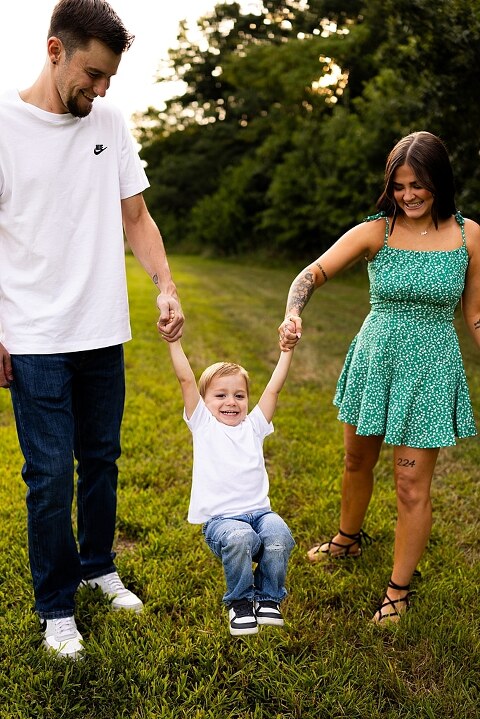 Family of three smiling together in a bright sunflower field during summer | Little boy grinning while standing among tall sunflowers
 | Parents holding their son and laughing in golden evening light | Family hugging closely surrounded by blooming sunflowers