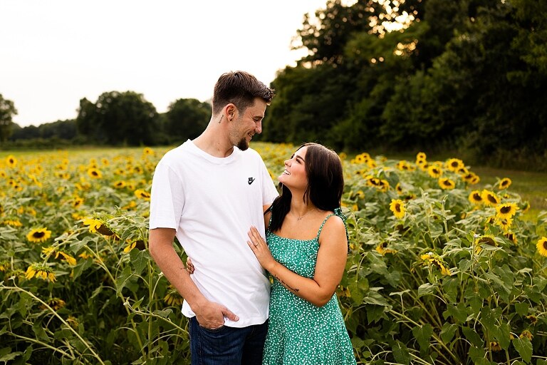 Family of three smiling together in a bright sunflower field during summer | Little boy grinning while standing among tall sunflowers
 | Parents holding their son and laughing in golden evening light | Family hugging closely surrounded by blooming sunflowers