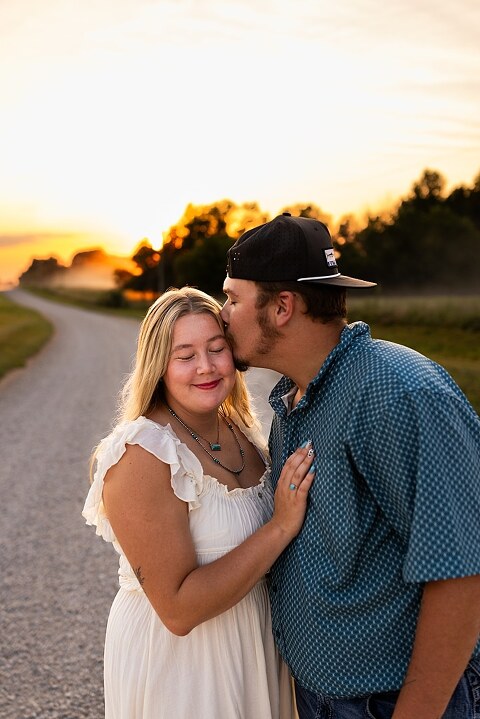 Couple walking hand in hand down a gravel road at sunset | Woman smiling at her partner during a country photo session | Former Missouri State Fair Queen posing with her partner in soft evening light | Close up of couple laughing while standing on a quiet country road