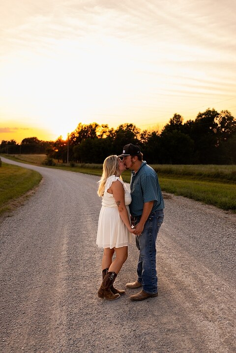 Couple walking hand in hand down a gravel road at sunset | Woman smiling at her partner during a country photo session | Former Missouri State Fair Queen posing with her partner in soft evening light | Close up of couple laughing while standing on a quiet country road