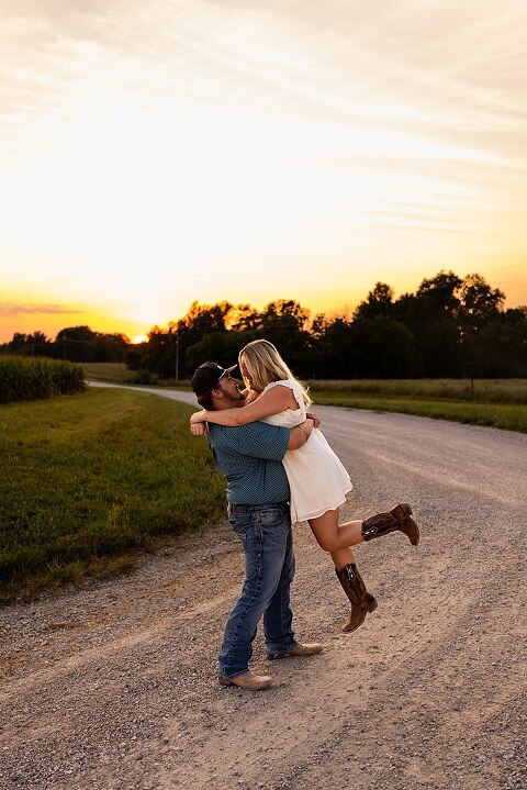 Couple walking hand in hand down a gravel road at sunset | Woman smiling at her partner during a country photo session | Former Missouri State Fair Queen posing with her partner in soft evening light | Close up of couple laughing while standing on a quiet country road