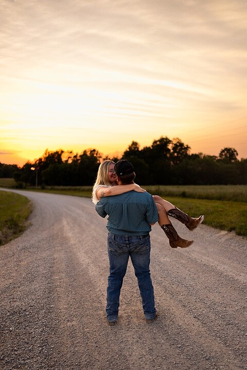 Couple walking hand in hand down a gravel road at sunset | Woman smiling at her partner during a country photo session | Former Missouri State Fair Queen posing with her partner in soft evening light | Close up of couple laughing while standing on a quiet country road