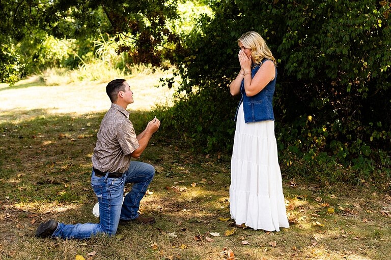 Tyler proposing to Rachel at Chandler Hill Vineyards in Defiance Missouri
Couple standing back to back moments before the surprise proposal
Rachel crying with joy as Tyler kneels during the proposal
Newly engaged couple hugging surrounded by vineyard scenery
Close up of engagement ring in front of rolling vineyard hills