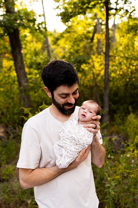 New parents holding their newborn girl outside in soft September light
Mother cradling newborn during an outdoor in home lifestyle session
Father smiling while holding baby girl in shaded backyard
Family photo with their dog photobombing in the background
Newborn resting peacefully with a curious kitty peeking nearby