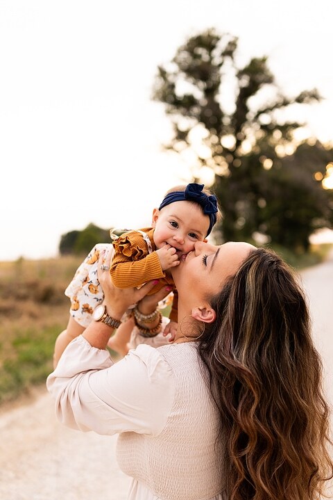 Oden Family walking together on a gravel road during a September photo session
Parents smiling at their children while standing on a country road
Children running and laughing down a gravel road in golden light
Family hugging closely with the soft glow of evening behind them